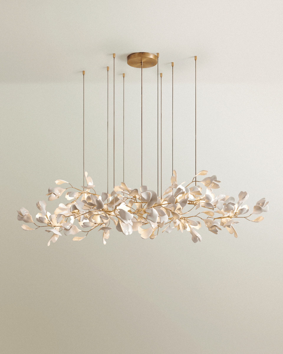 Clérachic long linear chandelier of white leaves on gold branches, hung from a round brass canopy on eight fine rods.