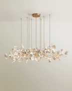 Clérachic long linear chandelier of white leaves on gold branches, hung from a round brass canopy on eight fine rods.