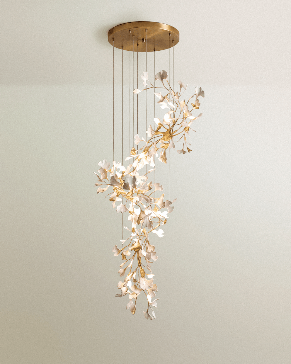 Clérachic tall cascading chandelier of white leaves on gold branches, dropping in tiers from a large round brass canopy.