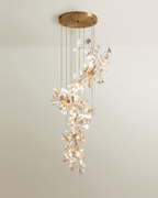 Clérachic tall cascading chandelier of white leaves on gold branches, dropping in tiers from a large round brass canopy.
