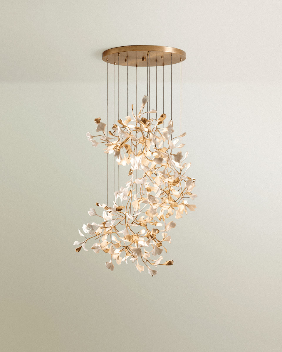 Clérachic spiralling cluster chandelier of white and gold leaves on branching stems under a round brass canopy.