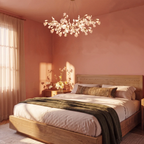 Clérachic leaf chandelier of white leaves hanging above a wooden bed in a terracotta-pink bedroom with a green throw.