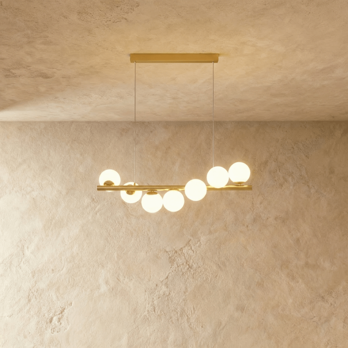Clérachic gold linear chandelier with seven opal white glass globes along a brass bar, hung from two fine wires and a bar canopy.