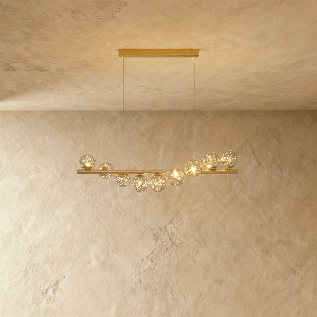 Clérachic gold linear chandelier with nine smoke-tinted glass globes glittering with small lights along a slim brass bar.