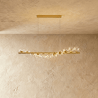 Clérachic gold linear chandelier with eleven clear glass globes sparkling with tiny lights, on a long brass bar and thin wires.