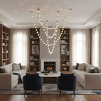 Several lit strands fall from a high ceiling in a double-height living room with bookshelves, a fireplace and cream sofas, lit by this Clérachic pendant.