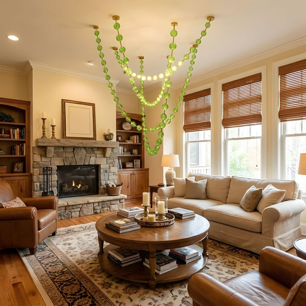 A green version of this Clérachic pendant hangs in layered lit loops above a round wooden coffee table in a warm room with a stone fireplace.
