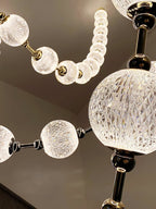 Detail of a large faceted glass sphere beside a string of smaller frosted beads, with dark metal connectors, on this Clérachic pendant.