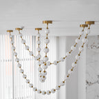 Looking up, frosted and cut-pattern spheres on gold links drape in several loops across sheer white curtains on this Clérachic pendant.