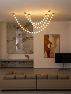 A wider view of this Clérachic pendant lit at dusk above a marble wall, a low ledge, a flat-screen TV and a taupe sofa.