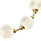 Product close-up on white of three cut-pattern clear spheres joined by brushed gold rods, the building block of this Clérachic pendant.