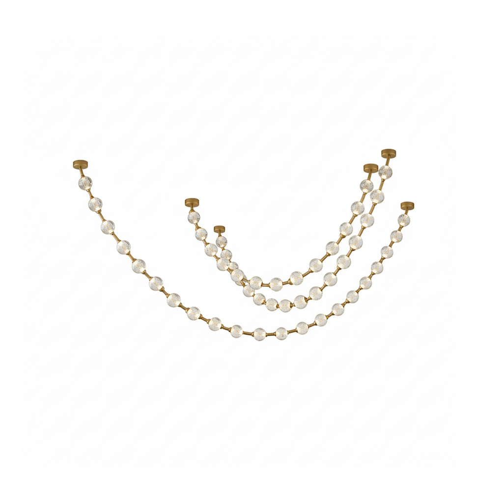 Three shallow swags of clear spheres on gold links hang from small brass plates on white, shown for this Clérachic pendant.
