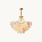 A Clérachic pendant light with tiers of overlapping pink and frosted glass discs, strands of pearls and a gold canopy, on a white backdrop.