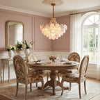 This Clérachic pendant hangs in a dining room with rose-pink walls, a round wooden table and floral-upholstered chairs below it.