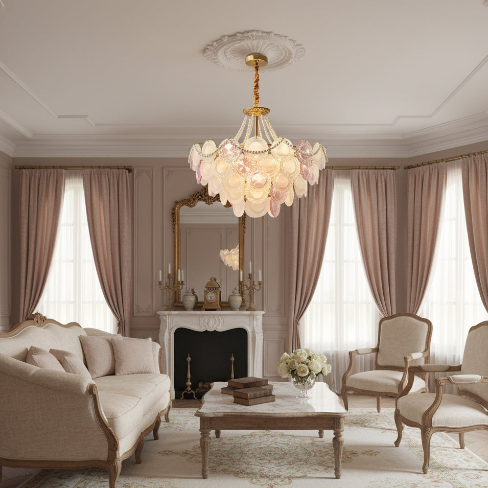 A Clérachic pendant with pink and frosted discs hangs in a living room with a cream sofa, pink curtains and a marble fireplace.