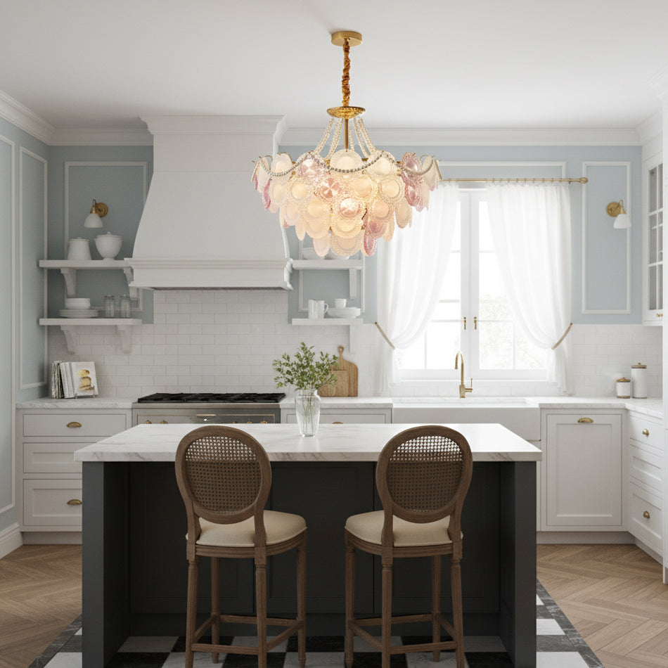 Clérachic glass-disc pendant above a white kitchen island with two cane bar stools, with pale blue walls and sheer curtains behind.