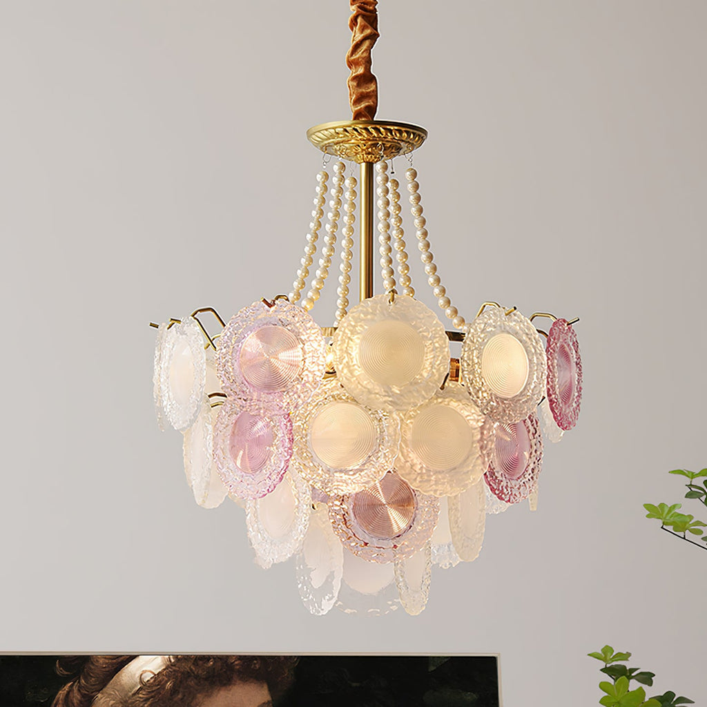 Looking up at a Clérachic pendant with pearl strands, a gold canopy and layers of pink and frosted glass discs, with a leafy branch in the corner.