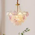 This Clérachic pendant glows warm on a pale wall, its pearl swags looping over rows of rose-tinted and frosted glass discs.
