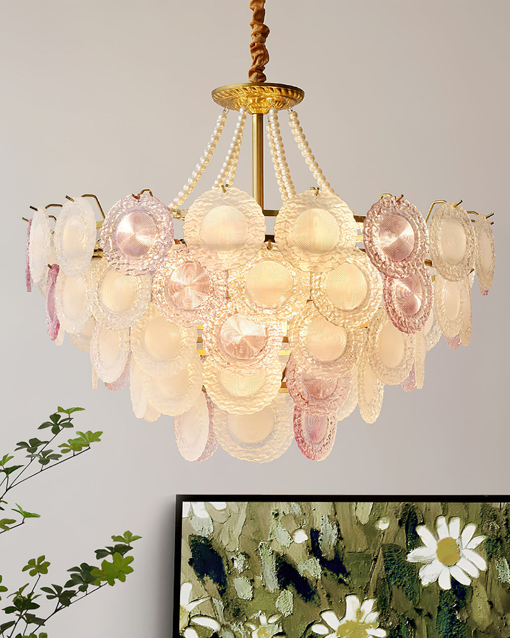 A wider view of the Clérachic glass-disc pendant lit, with leafy stems below and a framed floral picture at the lower edge.