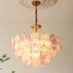 Close upward view of a lit Clérachic pendant under a ceiling rose, showing the textured glass discs and the gold canopy.
