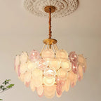 This Clérachic pendant lit under a ceiling rose, with warm light behind the pink and frosted discs and the pearls above them.