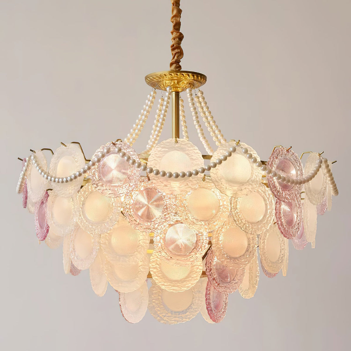 A Clérachic pendant filling the frame, with textured pink and frosted glass discs, pearls and a twisted gold-coloured chain.