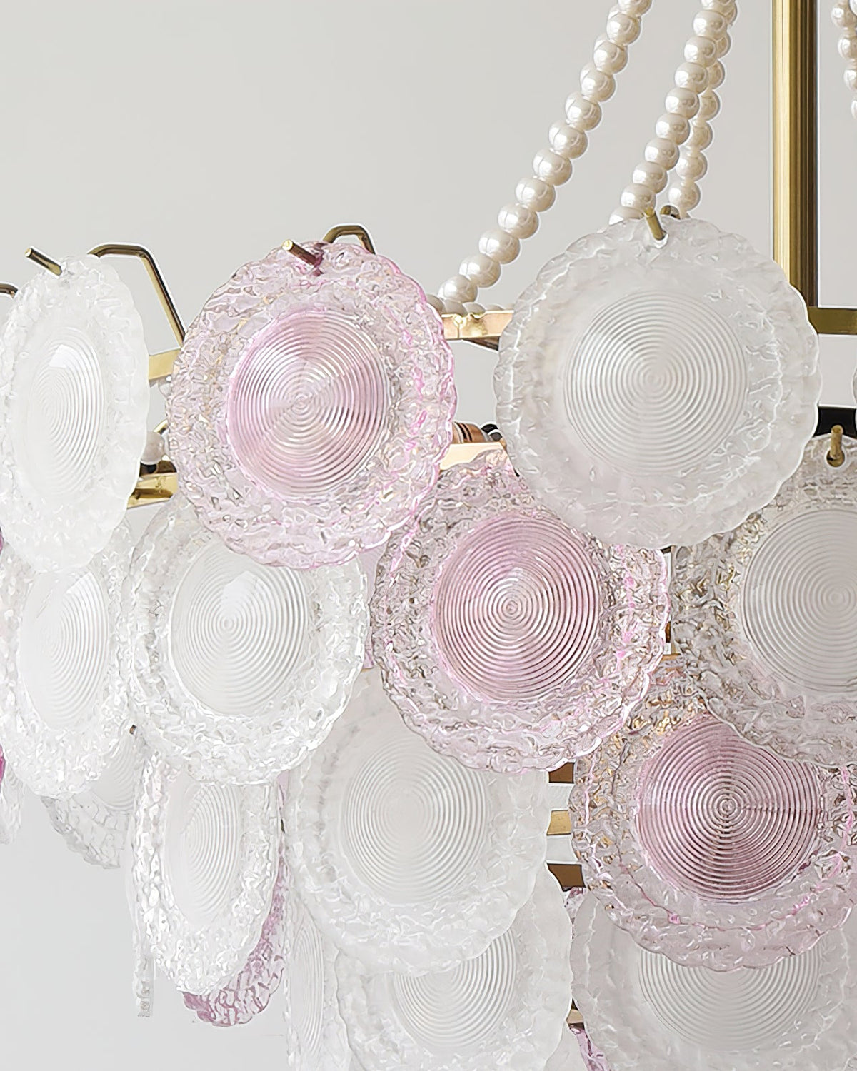 Close view of the concentric ridges on the pink and frosted glass discs of this Clérachic pendant, with pearls beside them.