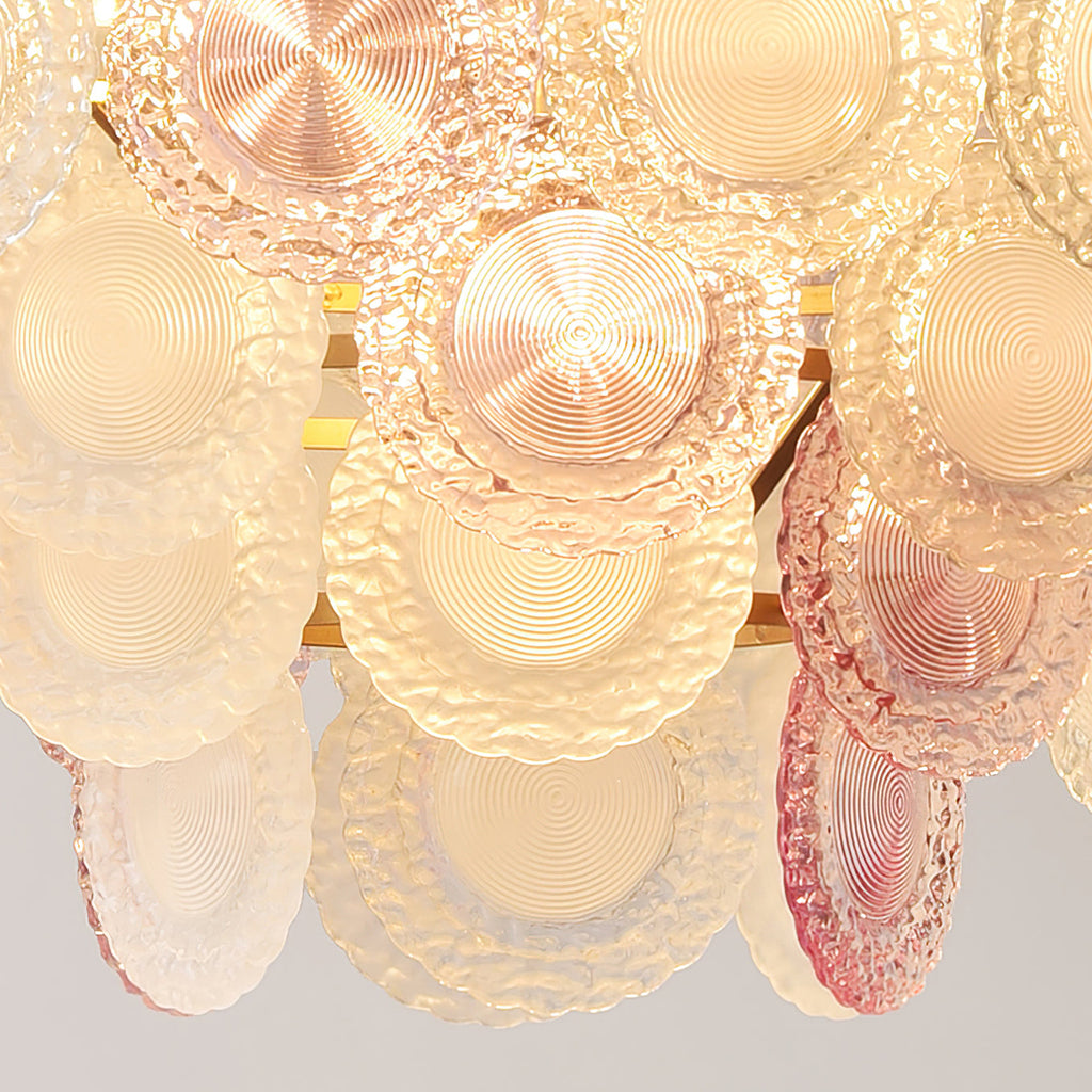 Close view of the ridged pink and frosted glass discs on this lit Clérachic pendant, glowing amber from inside.