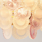 Close view of the ridged pink and frosted glass discs on this lit Clérachic pendant, glowing amber from inside.