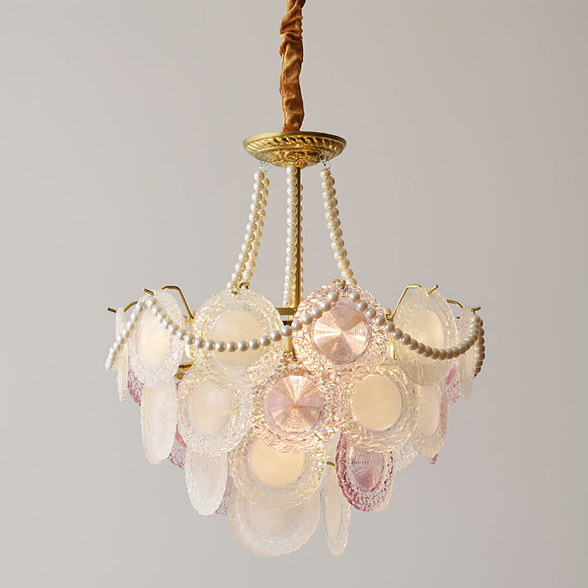 Clérachic pendant with tall pearl strands and fewer glass discs, glowing warm on a plain grey backdrop.