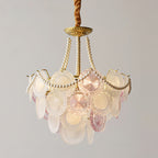A lit Clérachic pendant shown with tall pearl strands and pale glass discs in soft pink and white, on a grey backdrop.