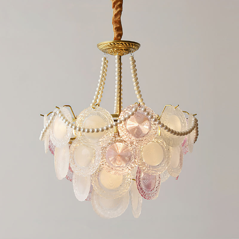 A lit Clérachic pendant shown with tall pearl strands and pale glass discs in soft pink and white, on a grey backdrop.