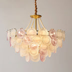A lit Clérachic pendant filling most of the frame, with a gold canopy, pearl strands and pink and frosted glass discs in tiers.