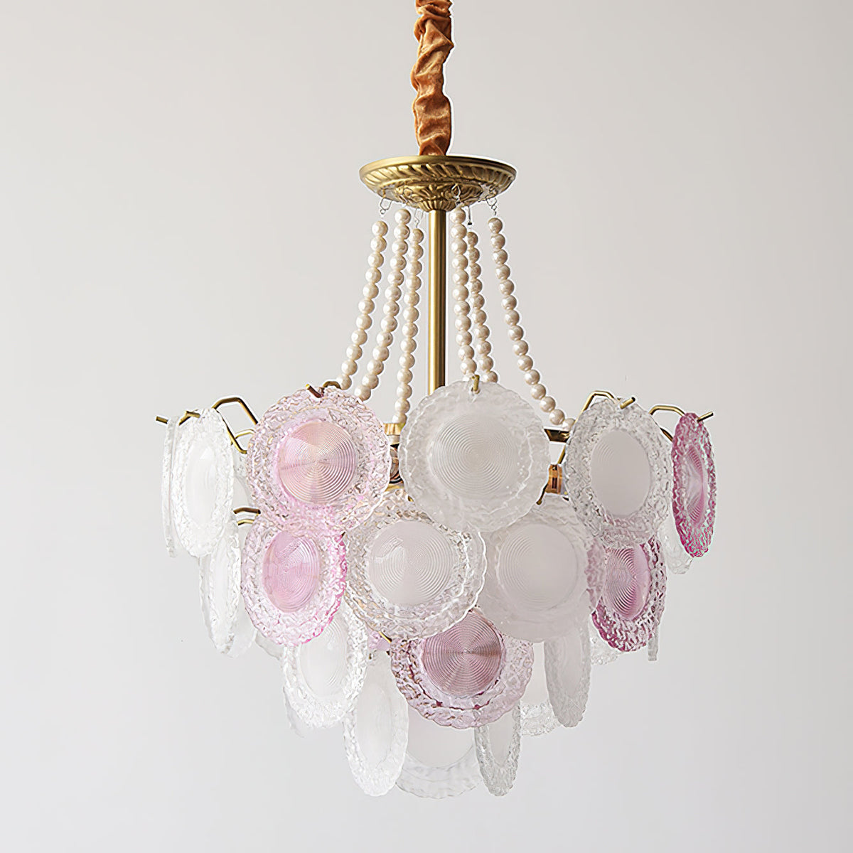 This Clérachic pendant unlit against a pale grey backdrop, its clear and pink-tinted discs hanging from pearl strands and a gold canopy.
