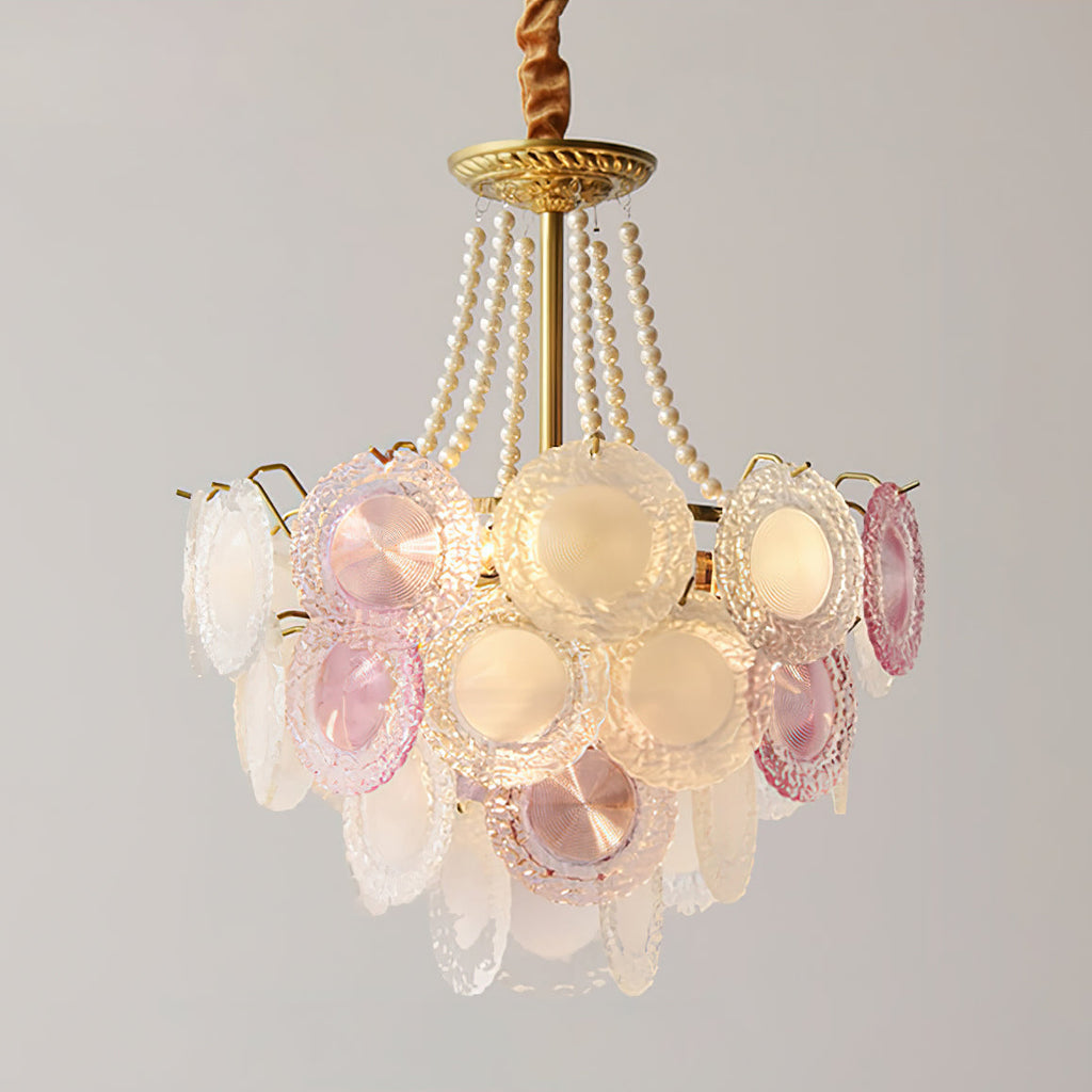 A Clérachic pendant lit with a gold canopy and pearl strands, showing glowing frosted discs and a few pink ones near the centre.