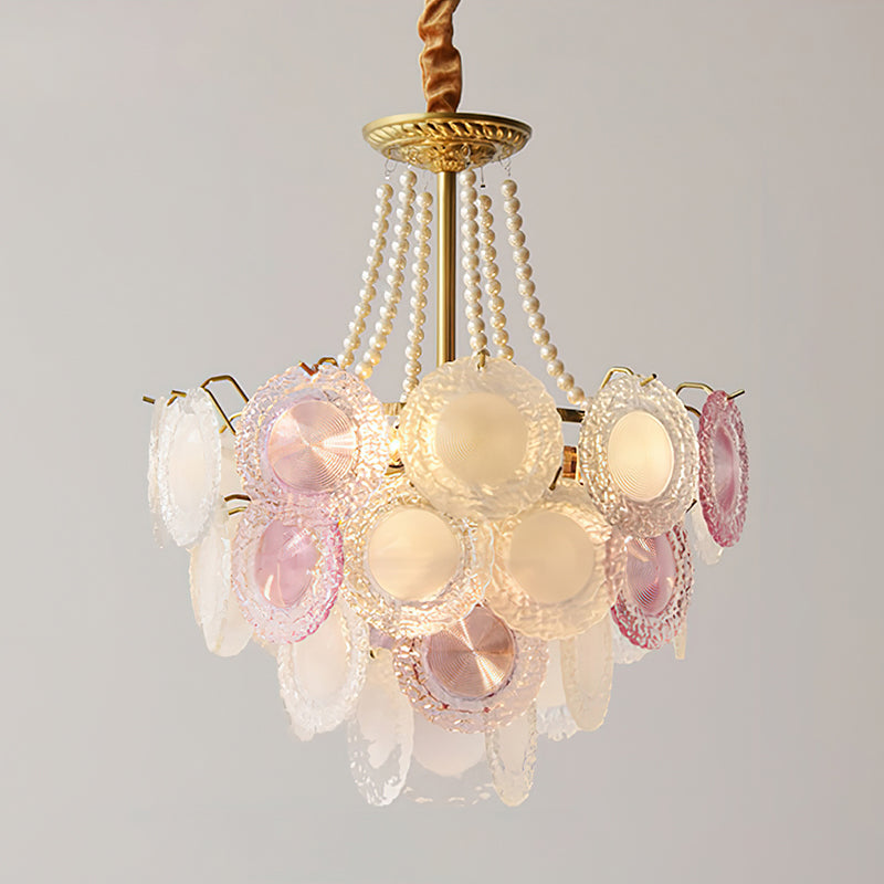 A Clérachic pendant with pearl strands and a gold canopy, lit, with rose-tinted discs in the front row and frosted ones behind.