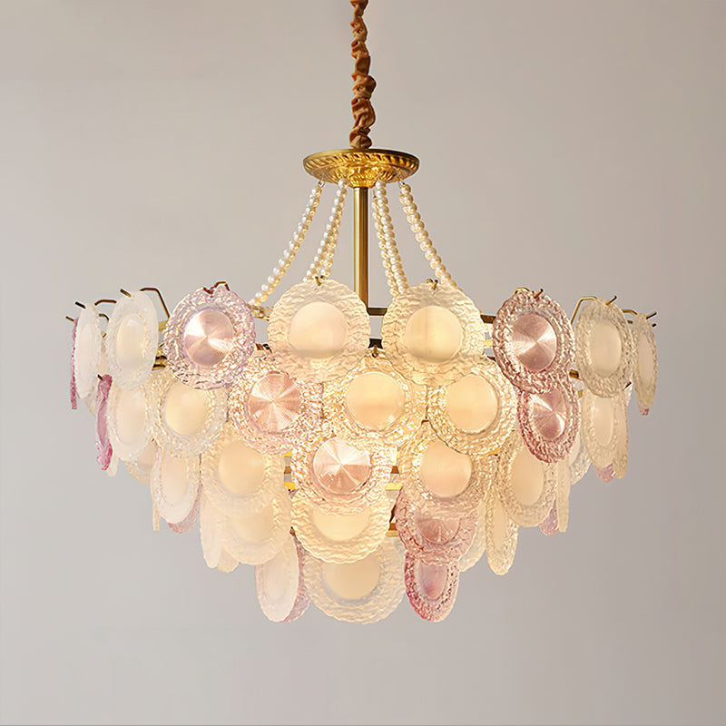 Wide Clérachic pendant lit on a grey backdrop, with a broad tier of pink and frosted glass discs and pearl strands above.