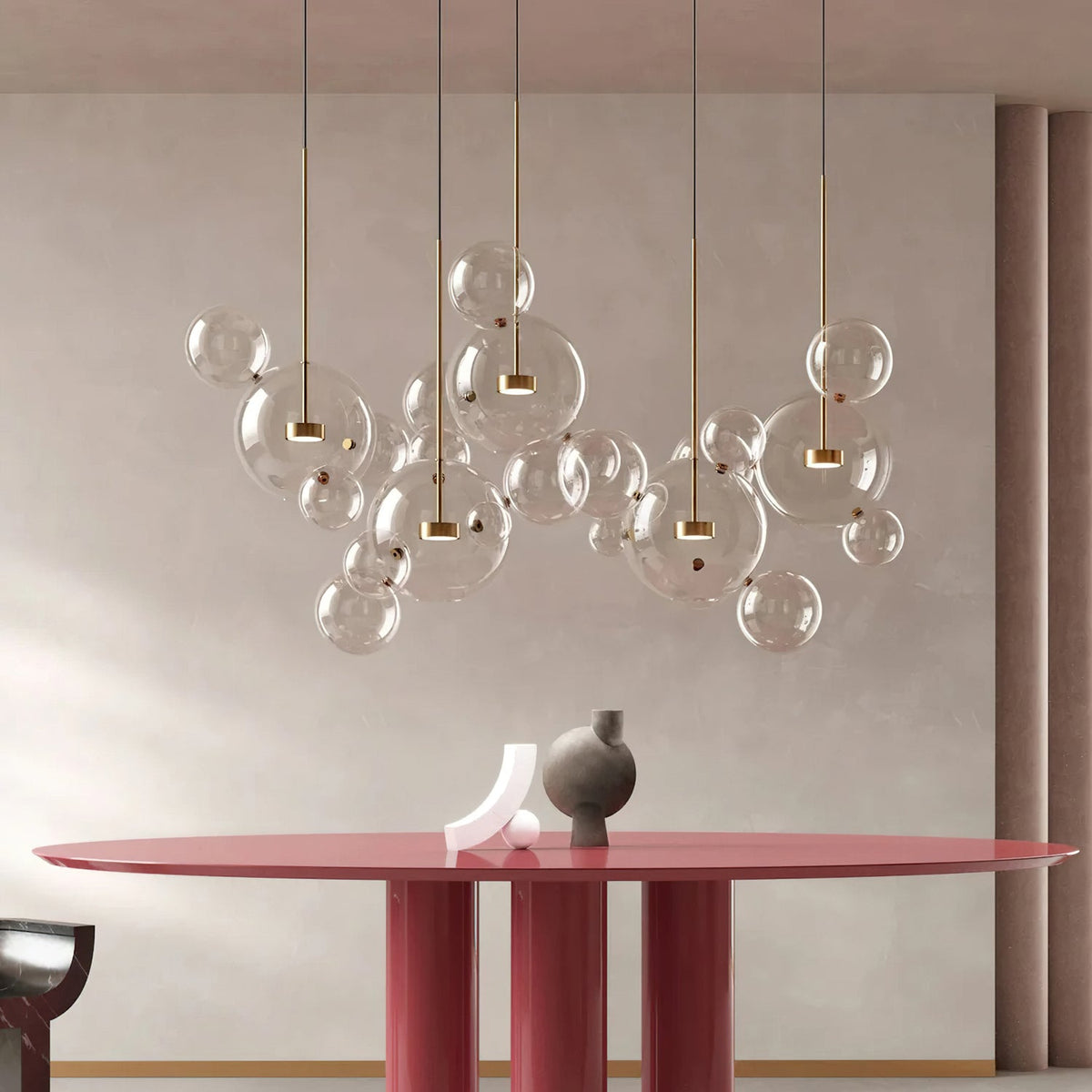 A cluster of Clérachic clear glass sphere pendants with gold stems, hung over a dusty-red round dining table.