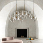 Clérachic clear glass sphere pendants in a row beneath a plastered arch, above a pink velvet seat and a fireplace.