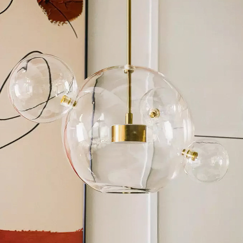 Close view of this Clérachic clear glass pendant, with a gold disc inside the large sphere and smaller spheres attached.