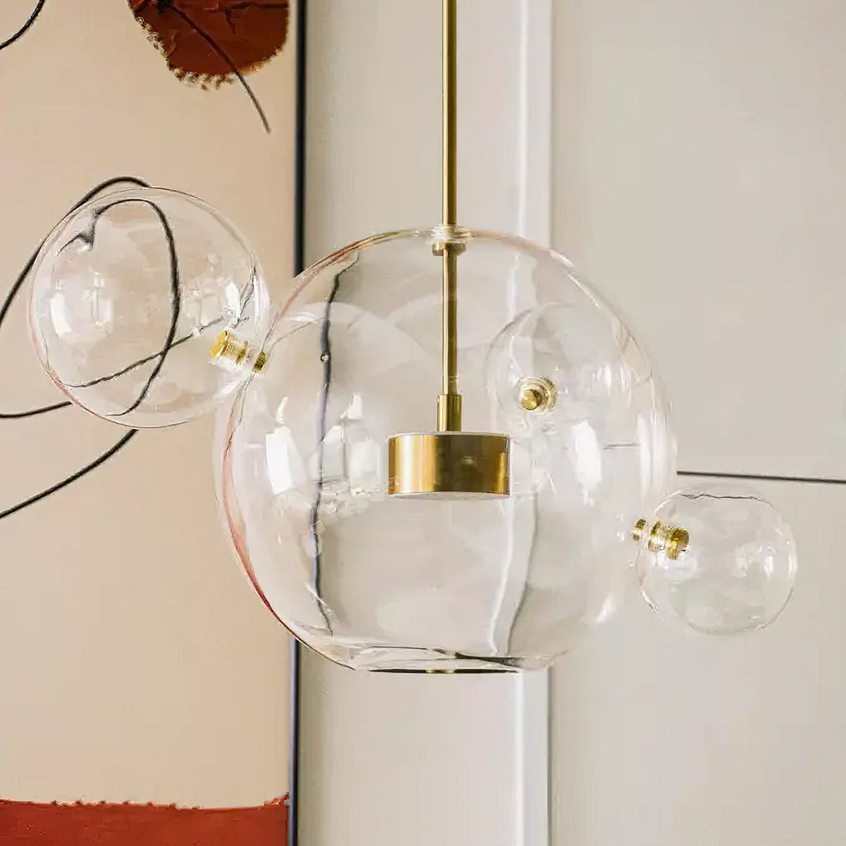 Close view of this Clérachic clear glass pendant, with a gold disc inside the large sphere and smaller spheres attached.
