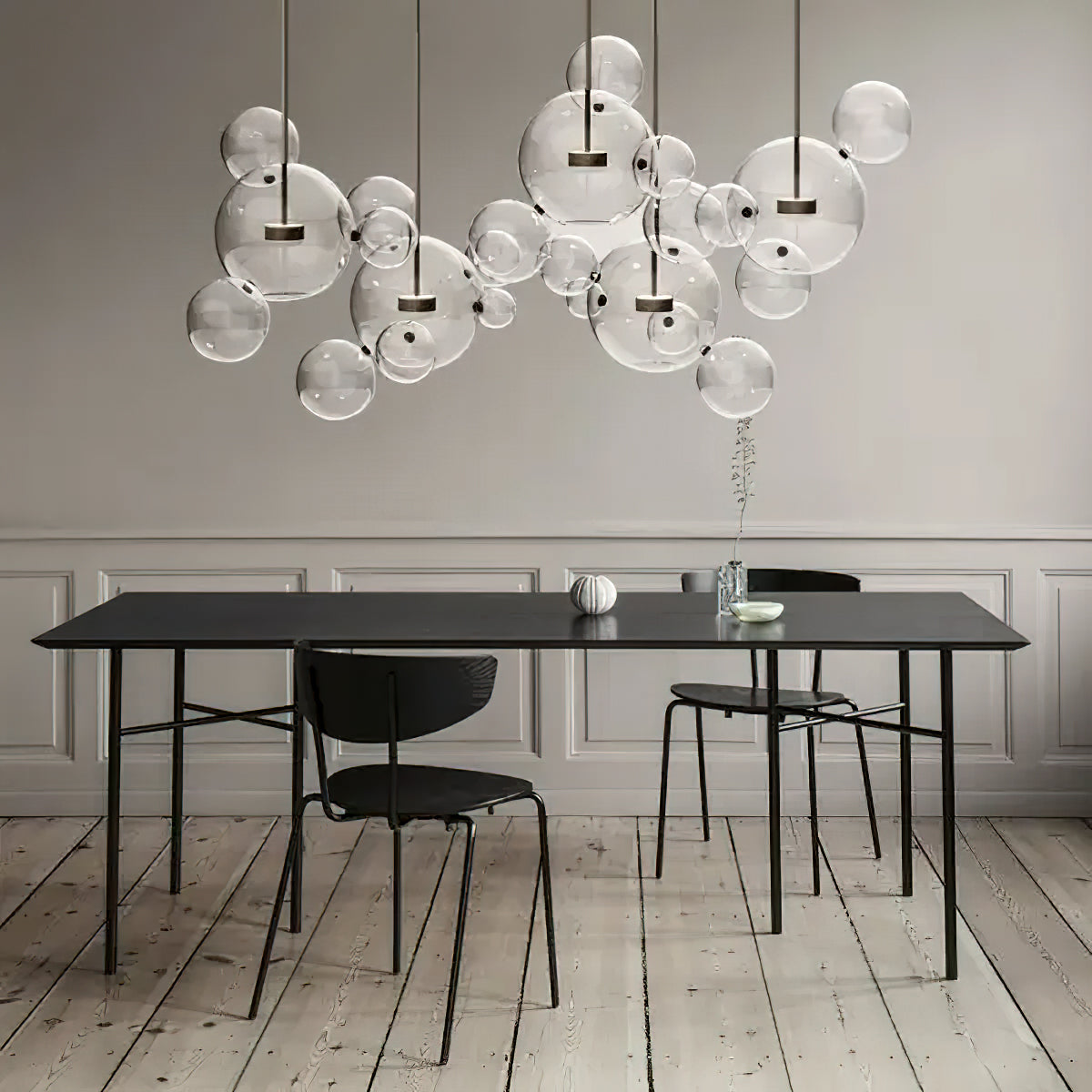 Wide cluster of Clérachic glass sphere pendants above a black dining table, with black chairs on a pale wooden floor.
