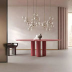 Clérachic glass sphere pendants hung above a dusty-red round table in a pale room with a fluted wall panel.
