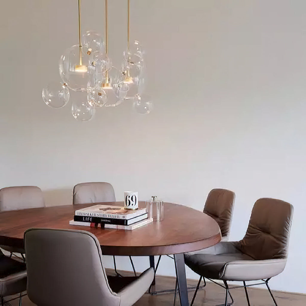 A small cluster of Clérachic glass sphere pendants over a round wooden table with leather chairs, against a white wall.