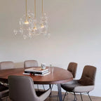 A small cluster of Clérachic glass sphere pendants over a round wooden table with leather chairs, against a white wall.
