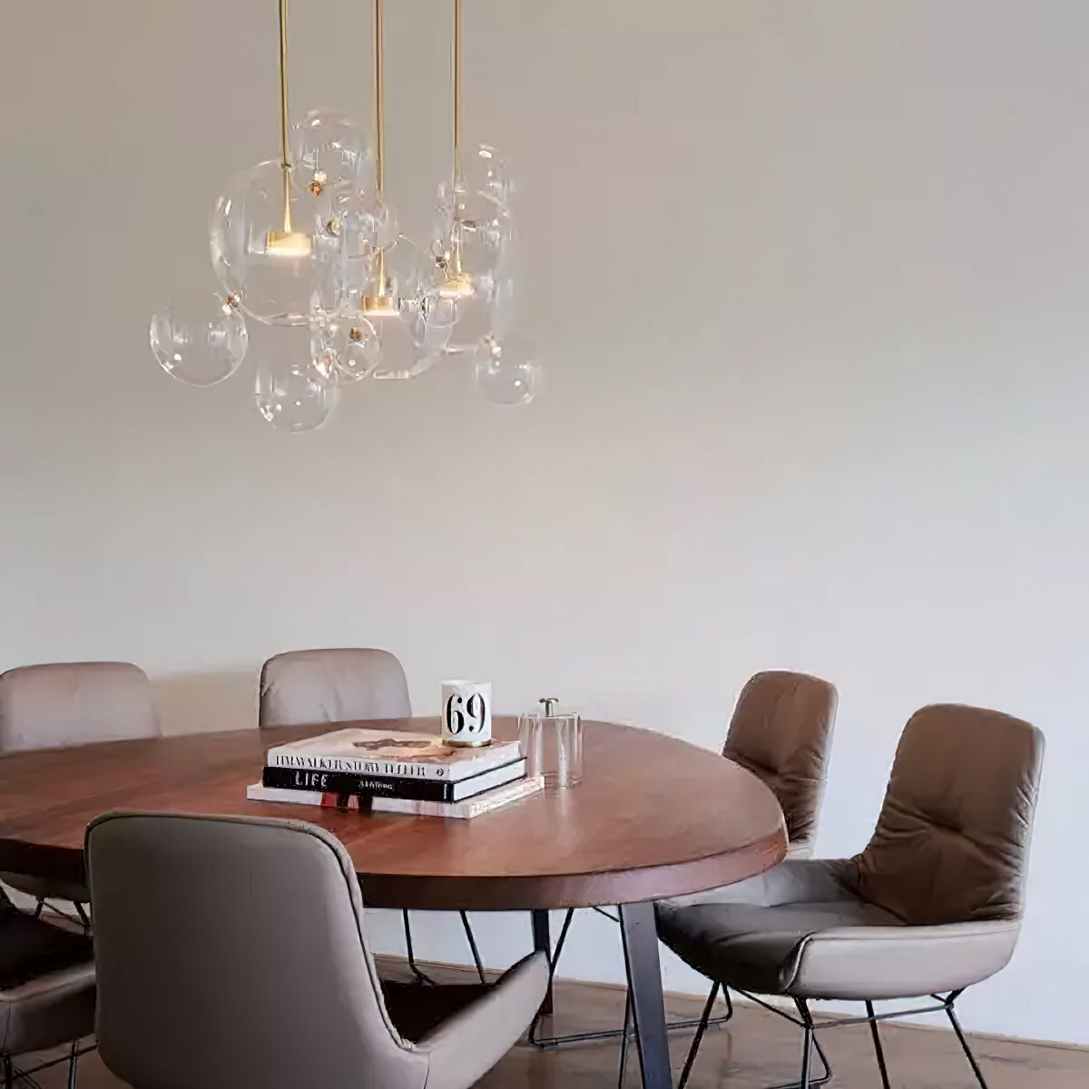 A small cluster of Clérachic glass sphere pendants over a round wooden table with leather chairs, against a white wall.