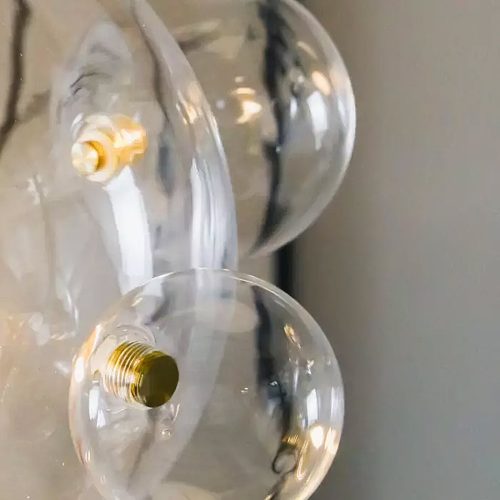 Close view of the gold fixing screws joining the clear glass spheres on this Clérachic pendant.