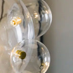 Close view of the gold fixing screws joining the clear glass spheres on this Clérachic pendant.
