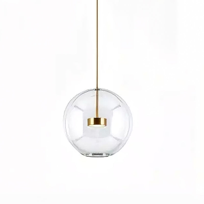 Single Clérachic clear glass globe pendant with a gold disc at its centre and a slim gold stem, on a white backdrop.
