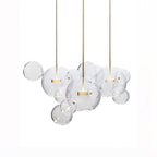 Three Clérachic glass sphere pendants with gold stems, clear spheres overlapping between them, on a white backdrop.